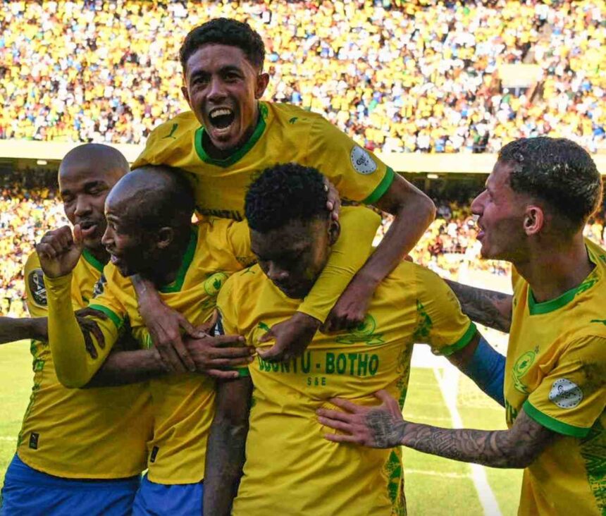 Soccer players in yellow jerseys celebrate a goal huddling together as teammates lift one player amid a cheering crowd  trybalnews