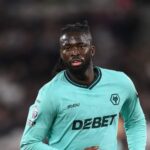 Football player in a teal Wolverhampton kit on the pitch sweat glistening with DEBET sponsor across the chest and a wolf crest visible on the jersey  trybalnews