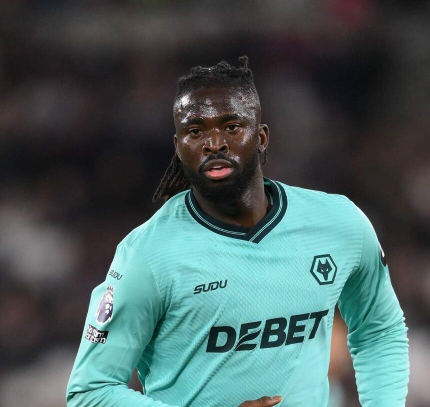 Football player in a teal Wolverhampton kit on the pitch sweat glistening with DEBET sponsor across the chest and a wolf crest visible on the jersey  trybalnews