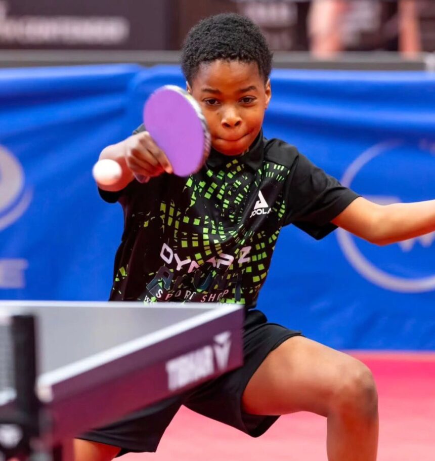 Young table tennis player in a black and green shirt lunges to hit a pink paddle at a ping pong ball focused on the shot on a table tennis table  trybalnews