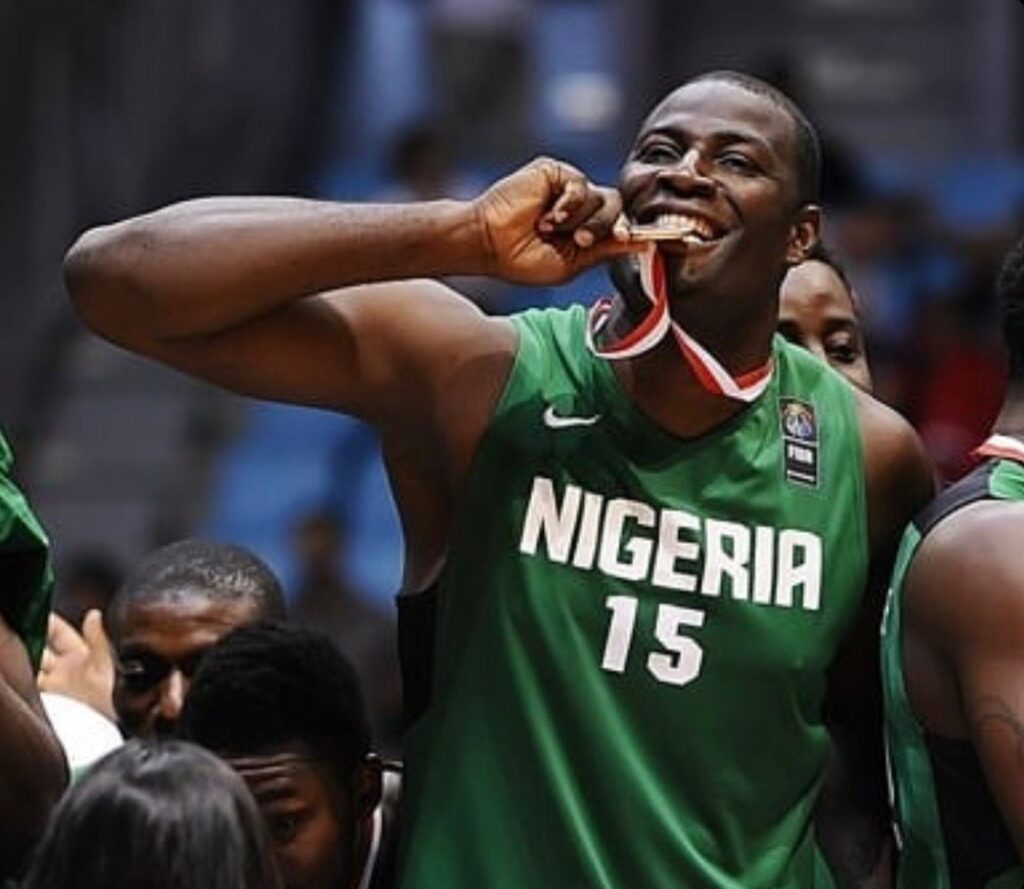 Nigerian basketball player in a green jersey biting a medal during celebration jersey number 15  trybalnews