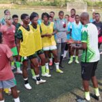 Coach speaking to a group of young soccer players wearing yellow bibs on a turf field  trybalnews