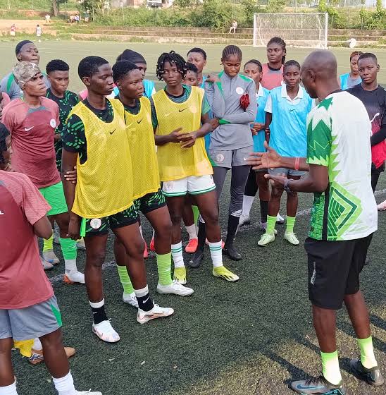 Coach speaking to a group of young soccer players wearing yellow bibs on a turf field  trybalnews