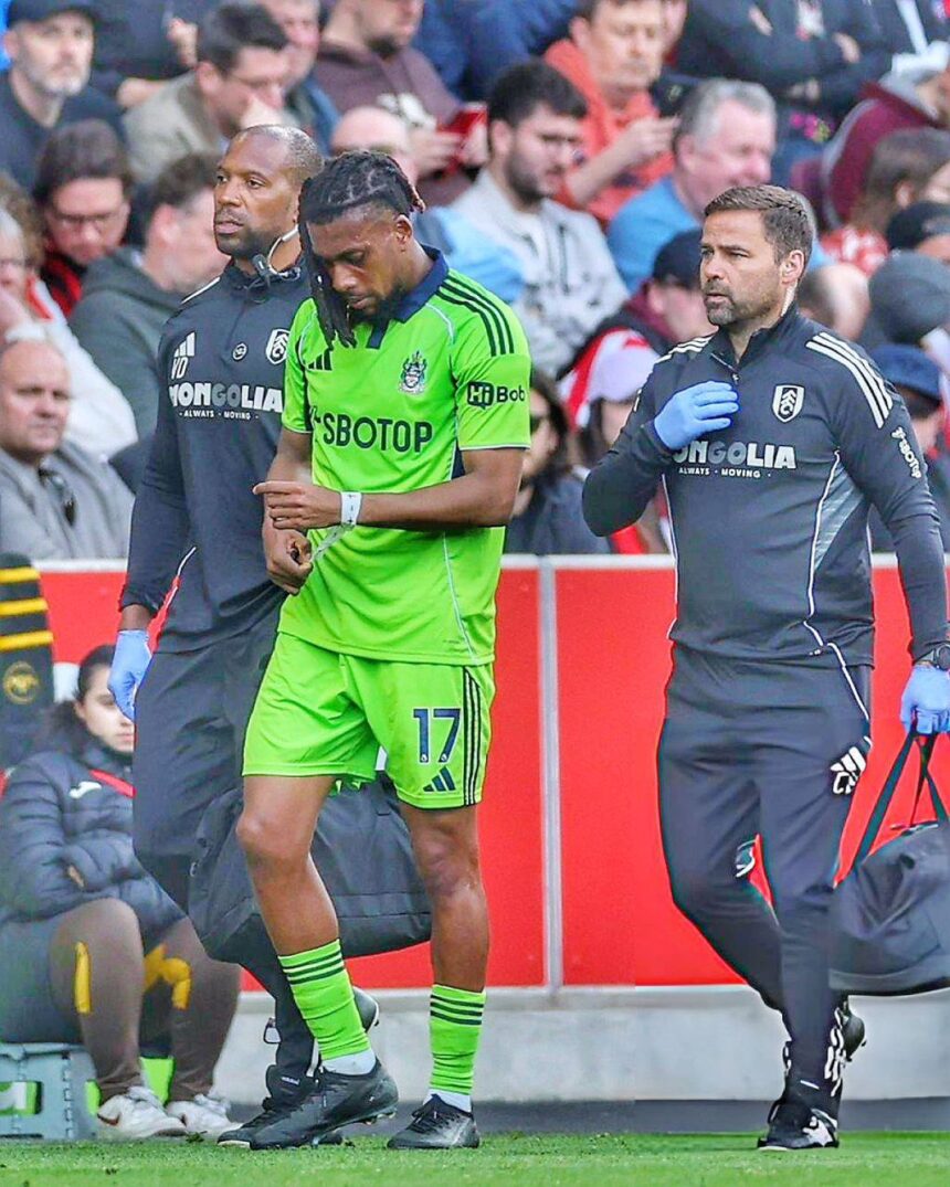 Soccer player in neon green kit 17 walking off the field with two team staff members in dark jackets beside him  trybalnews