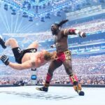 Two muscular wrestlers clash in a packed arena one fighter flips backward as the other delivers a kick  trybalnews