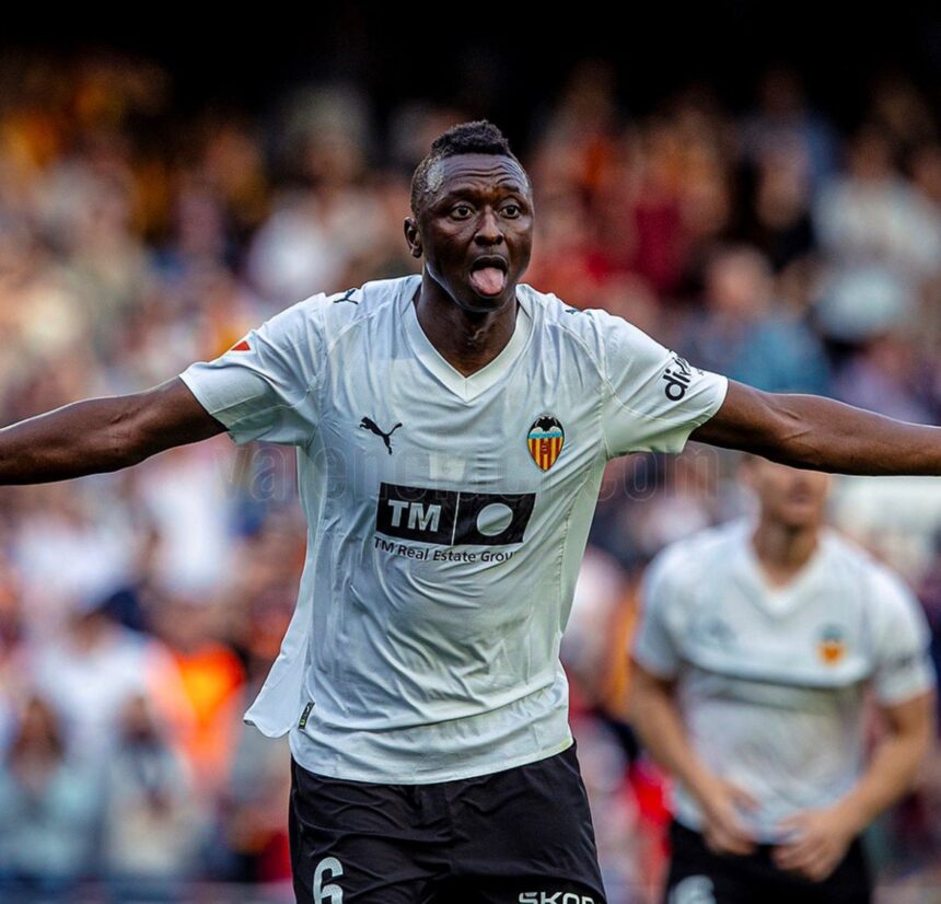 Valencia CF footballer celebrating with arms spread wide and tongue out on the pitch crowd behind him  trybalnews