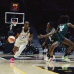 Female basketball player in white jersey dribbles toward the basket pursued by green jersey defenders on a polished court  trybalnews