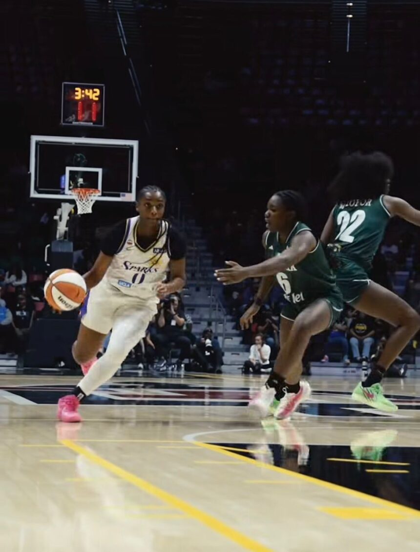 Female basketball player in white jersey dribbles toward the basket pursued by green jersey defenders on a polished court  trybalnews