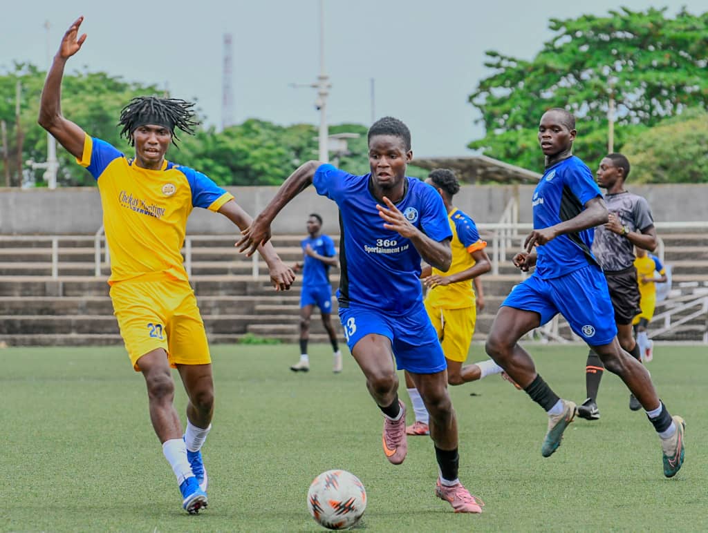 WhatsApp Image 20260427 at 095510 Trybal News Young soccer players in blue and yellow uniforms chase a ball on a green field during a match with a referee in the background trybalnews