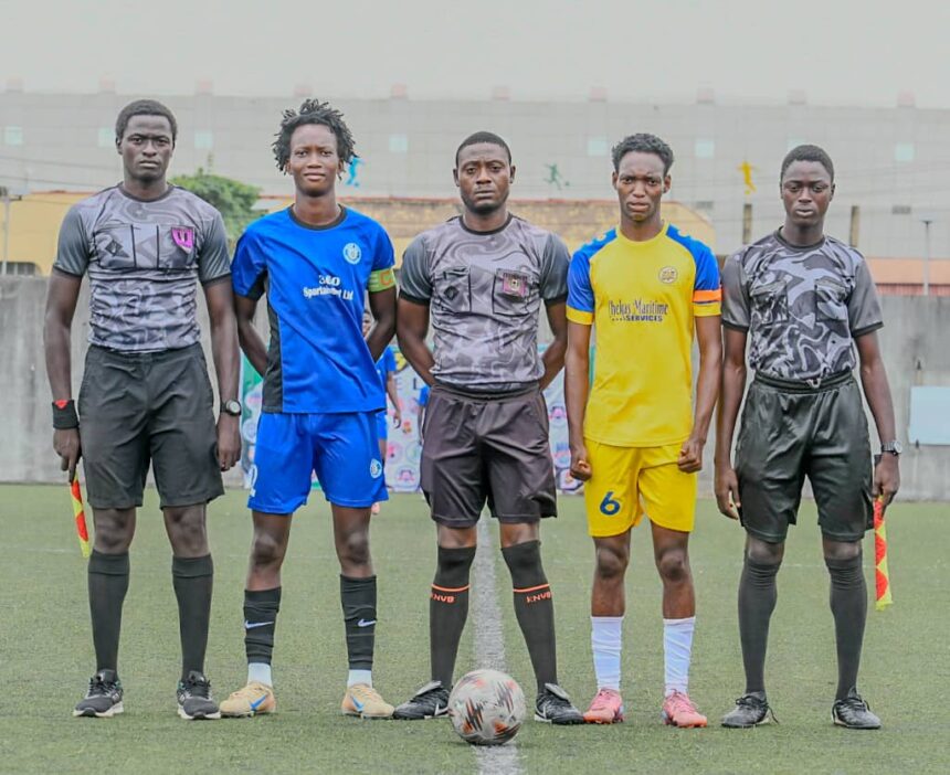 Five young men in soccer kits stand in a line on a field with a ball at their feet ready for kick off Behind them is a stadium wall  trybalnews