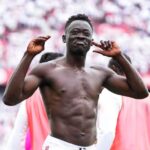Athlete in a stadium celebration shirtless with hands raised near his ears as the crowd cheers behind him  trybalnews
