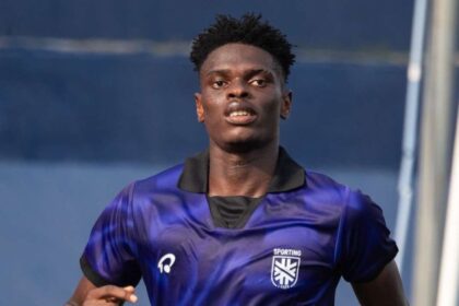 Male athlete in a blue gradient soccer jersey runs forward on a field, Sporting crest visible on chest.