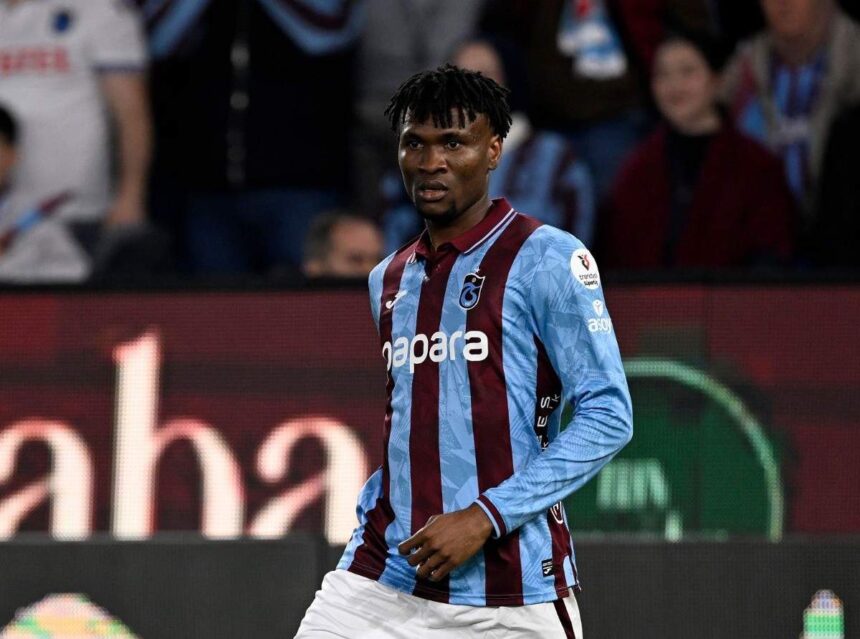 Professional footballer in blue and maroon striped jersey running on a soccer field with spectators in the stands behind him  trybalnews