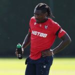 Soccer player in a red training top with NET88 holding a water bottle during practice  trybalnews