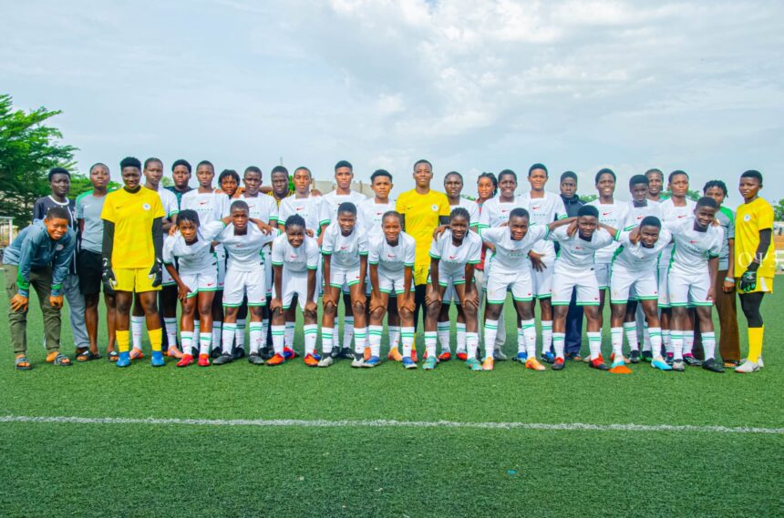 Wide group of young soccer players posing on a green field in white kits with green trim plus yellow jersey goalkeepers under a cloudy sky  trybalnews