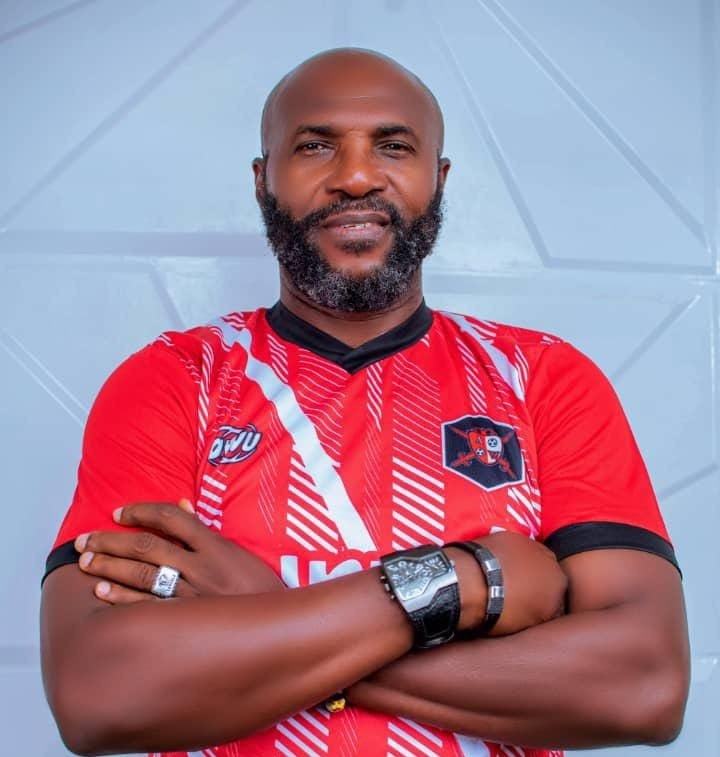 Man with a beard wearing a red sports jersey arms crossed standing against a light blue wall  trybalnews