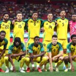 Jamaica national soccer team posing for a pre match team photo on a soccer field in yellow jerseys with green sleeves  trybalnews