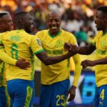 Soccer players in yellow jerseys celebrate together on the field arms around each other smiling  trybalnews
