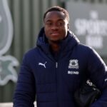 Young man in a navy puffer jacket with a crest and a Puma logo carrying a small black bag outdoors  trybalnews