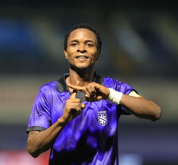 Soccer player in a purple jersey on a stadium field smiling and making a hand gesture with both hands to celebrate the moment  trybalnews