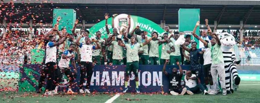 Soccer team and fans celebrate on the pitch holding a CHAMPION banner as confetti falls  trybalnews