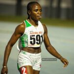 Female sprinter in a white and green athletic outfit with bib ACCRA 2026 and number 591 walking on a track after a race  trybalnews