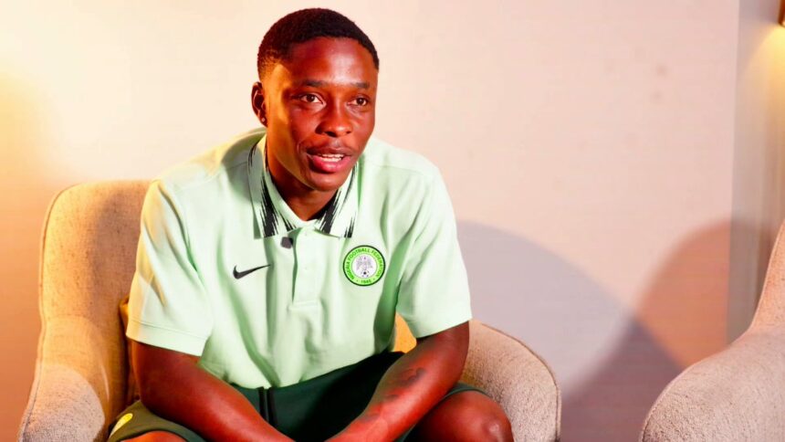 Young man in a mint green polo with a Nigeria Football Federation crest sitting in a beige armchair in a softly lit room  trybalnews