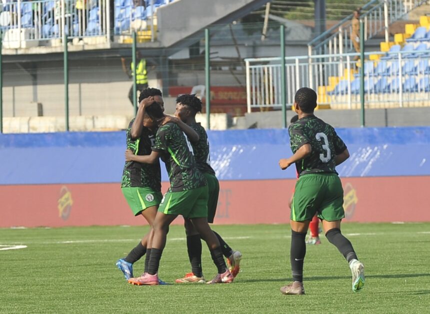 Soccer players in green uniforms celebrate on a grass field embracing each other after a goal as stadium seats loom in the background  trybalnews