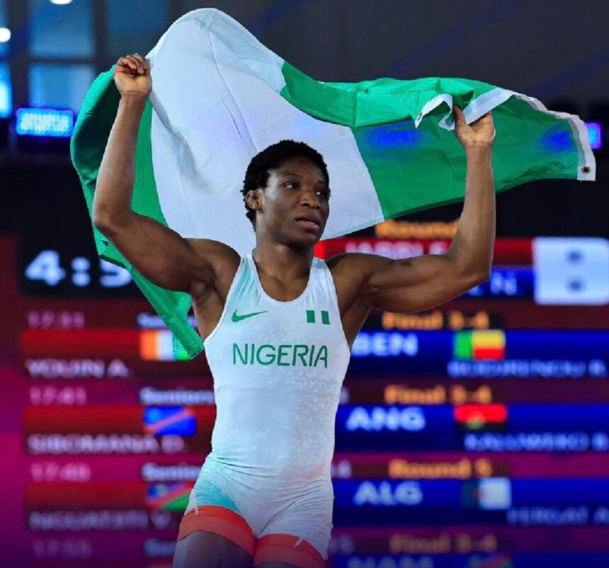 Nigerian athlete lifts the green white green flag in celebration on a podium or stage wearing Nigeria kit with NIGERIA visible  trybalnews