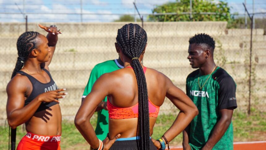 Athletes on a track field chat central figure is a woman with braided hair seen from behind  trybalnews