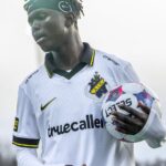 Soccer player in a white jersey with blackyellow trim holding a soccer ball under his right arm  trybalnews