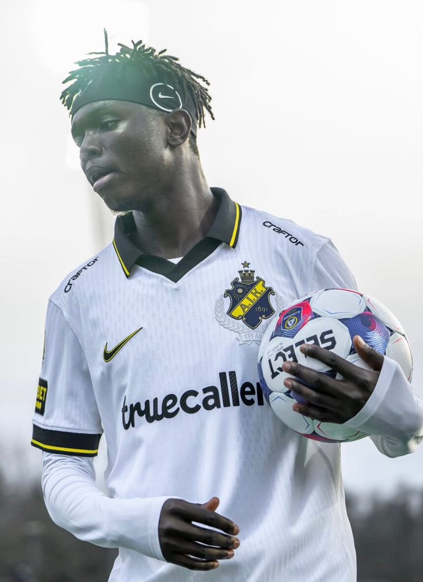 Soccer player in a white jersey with blackyellow trim holding a soccer ball under his right arm  trybalnews