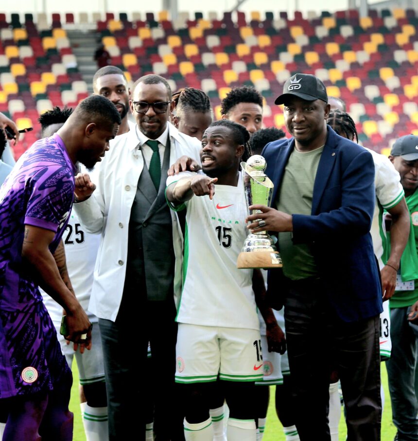 Group of soccer players posing with a trophy on the field after a match stadium seating in multicolored background  trybalnews