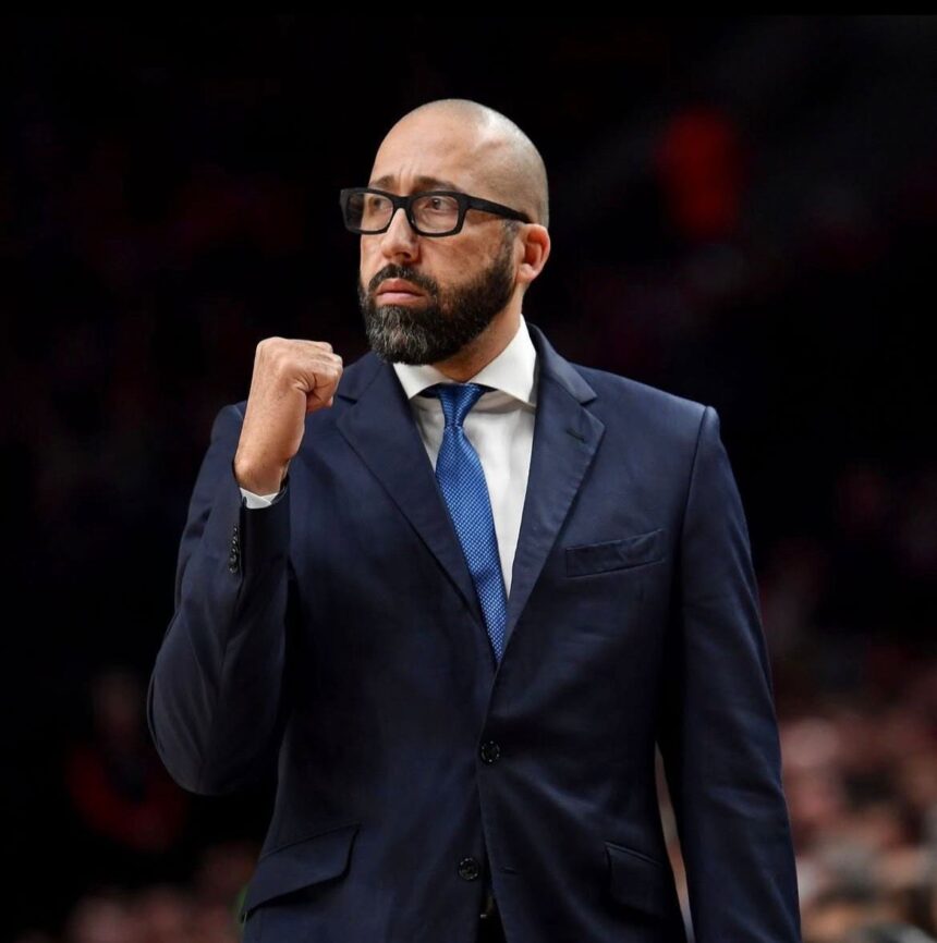 Bearded man in a navy suit and blue tie raising a clenched fist in a determined gesture at an event  trybalnews