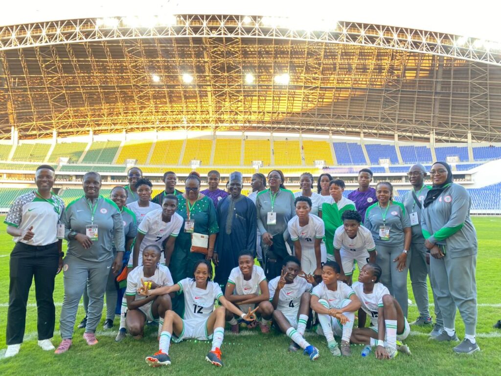 WhatsApp Image 20260509 at 164418 Trybal News Group of female soccer players and coaches posing on a green stadium field with colorful empty stands in the background trybalnews