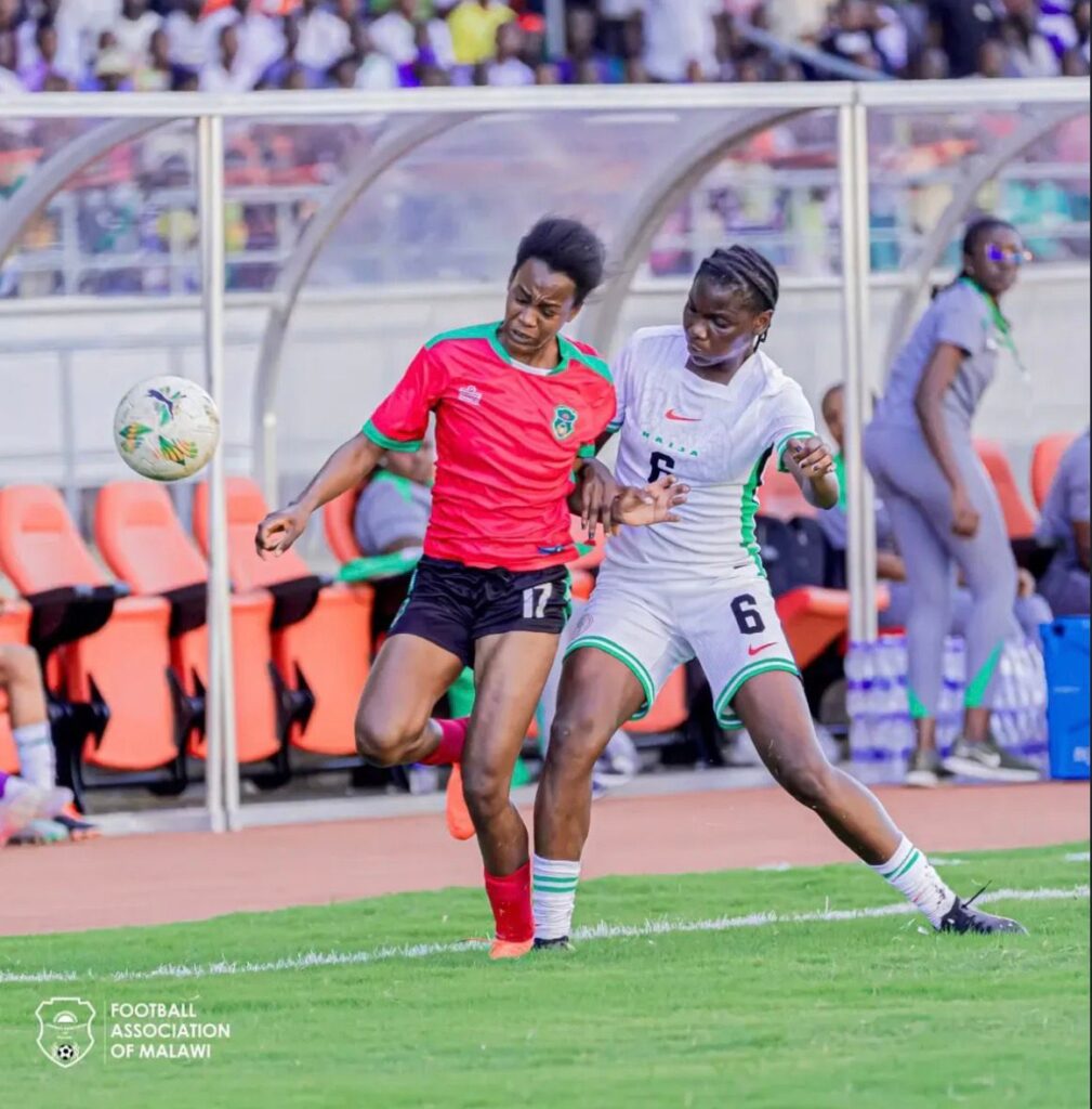 WhatsApp Image 20260509 at 164944 Trybal News Two female soccer players compete for the ball on a green field during a match one in red No17 and the other in white No6 with spectators in the stands behind them trybalnews