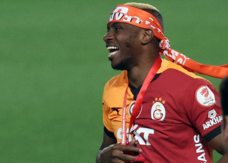 Soccer player in a red orange Galatasaray kit with a headband smiling on the field during a celebration  trybalnews