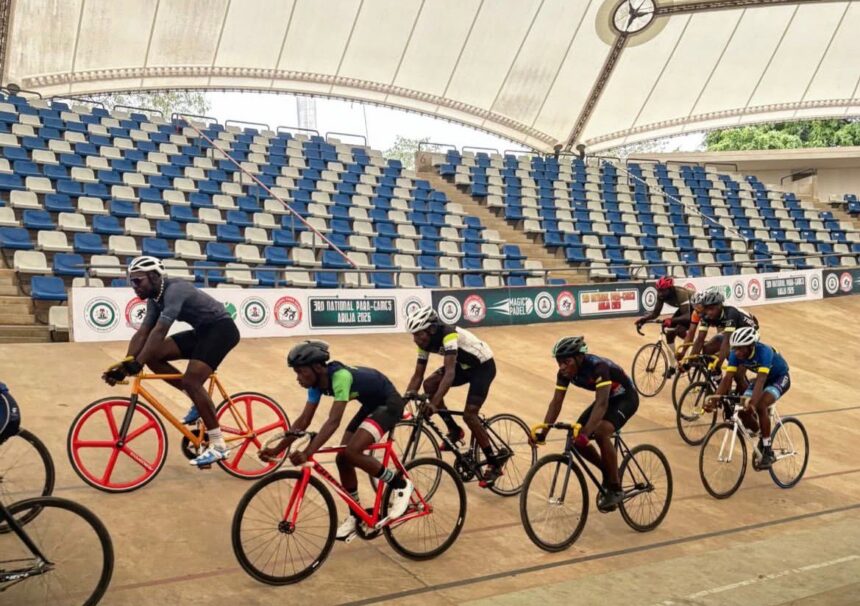 Group of cyclists racing on an indoor velodrome track under a curved roof with colorful bikes and helmets in a pack  trybalnews