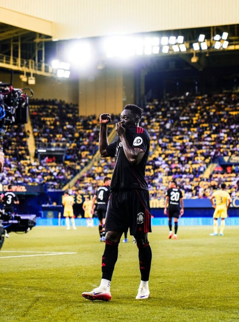 WhatsApp Image 20260513 at 213604 Trybal News Soccer player in black kit celebrating with fists raised on the field during a crowded stadium match trybalnews
