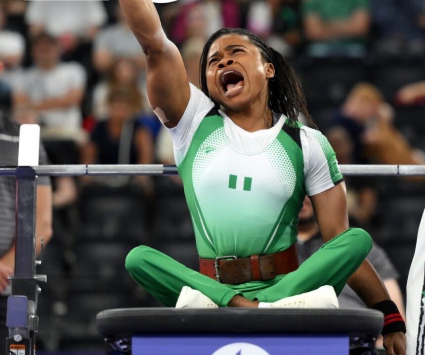 Female weightlifter celebrating on the platform after a lift shouting with arm raised  trybalnews