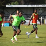 Football players in neon green kits sprint during a training drill on a grassy pitch with a ball nearby  trybalnews
