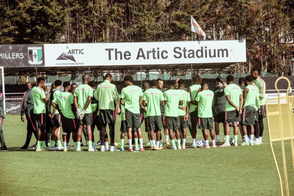 Soccer players in green training kits form a huddle on the field under The Artic Stadium sign  trybalnews