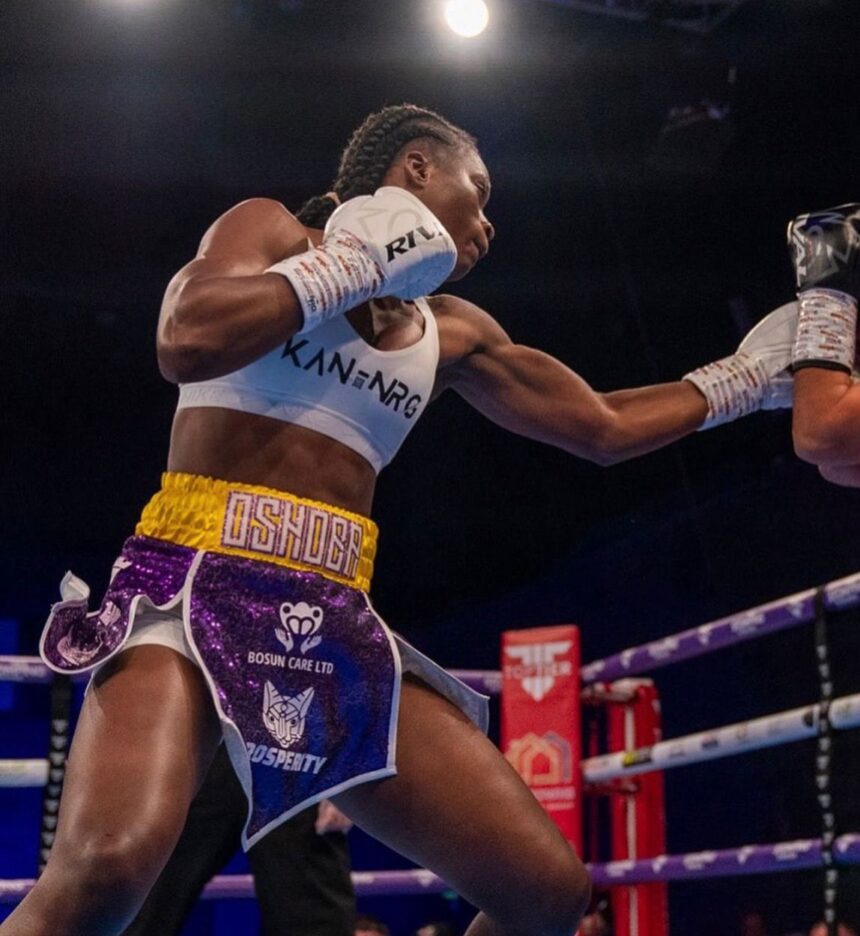 Female boxer wearing a white sports bra and colorful shorts throws a punch in a boxing ring A gloved fist connects as the opponents arm extends into view  trybalnews