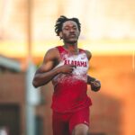 Male sprinter in Alabama red and white uniform mid race on a track with a focused expression  trybalnews