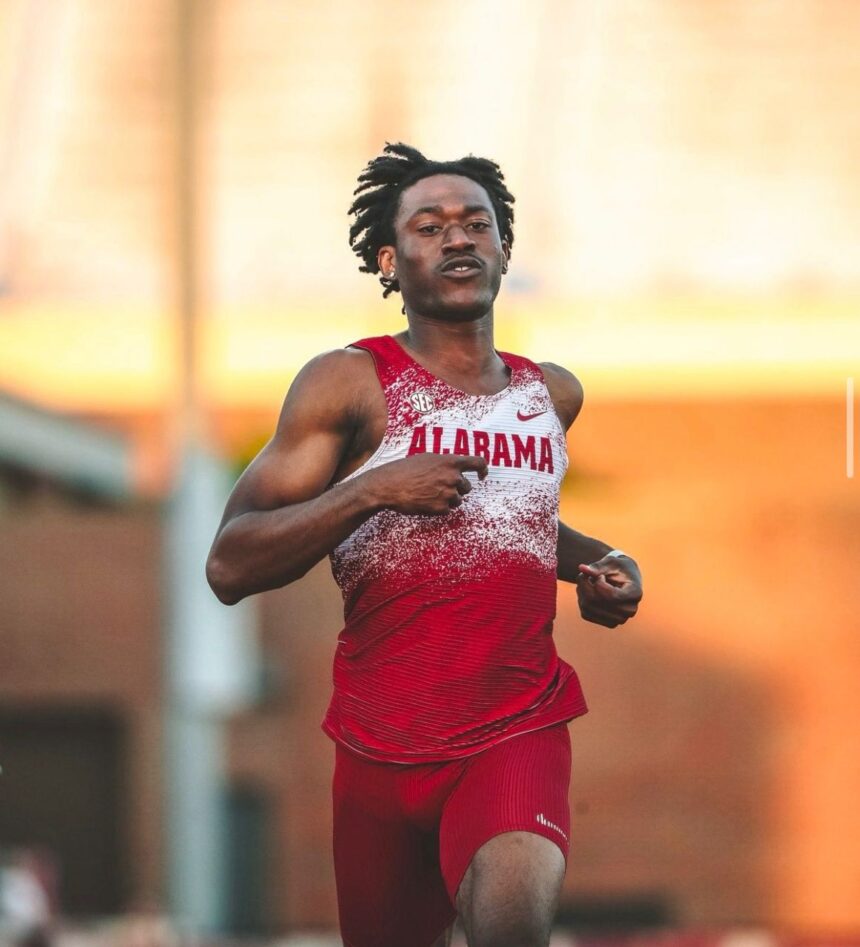 Male sprinter in Alabama red and white uniform mid race on a track with a focused expression  trybalnews