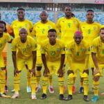 Senegal national football team players in yellow kits pose for a group photo on a soccer field with empty stadium seats behind them  trybalnews