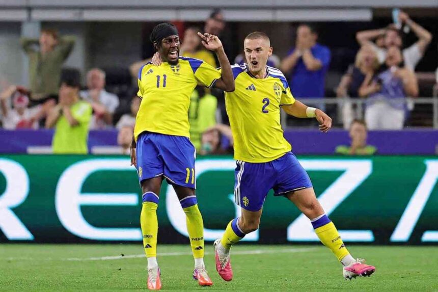 Sweden forward Anthony Elanga wearing yellow 11 jersey with blue shoulders blue shorts yellow socks and a black headband celebrates with teammate Gustaf Lagerbielke 2 Elanga is on the left with his mouth open shouting right arm raised and Lagerbielkes arm around his shoulder Lagerbielke wearing yellow 2 jersey and blue shorts runs beside him with his mouth open and left arm out Both wear matching yellow Adidas kits with Sweden crest and blue shorts FIFA World Cup 2026 Group F match between Japan and Sweden at Dallas Stadium Arlington Texas on June 25 2026 Blurred fans react in the background  trybalnews