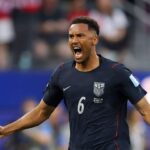 USA defender Auston Trusty wearing navy blue 6 Nike jersey with white USA crest and red trim celebrates with a roar He has short curly hair both fists clenched and arms spread wide with an intense expression FIFA World Cup 2026 Group D match between Türkiye and USA at Los Angeles Stadium Inglewood California on June 25 2026 Blurred crowd and blue stadium boards in the background  trybalnews