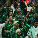 Crowd of band members in green patterned jerseys playing brass instruments at a stadium like event  trybalnews