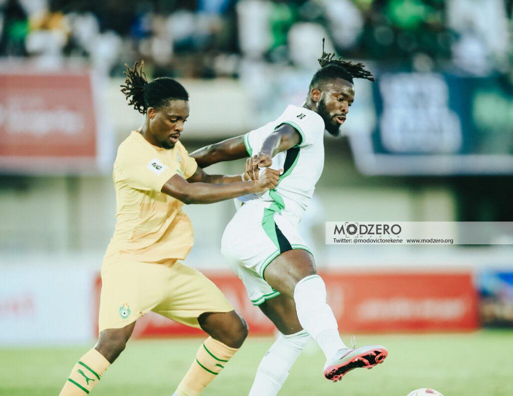 Nigeria vs Zimbabwe World Cup qualifier Kigali Rwanda Trybal News Two soccer players compete for the ball during a match one in yellow and the other in white and green trims close together on the field trybalnews